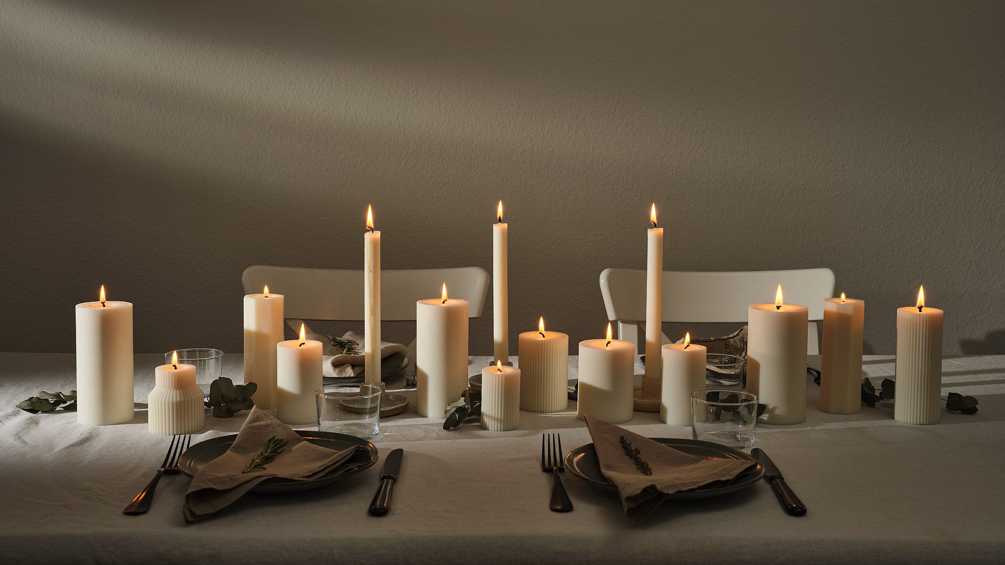 Stimmungsvolle Tischdekoration mit naturweissen Stab- und Zylinderkerzen, elegant arrangiert für ein gemütliches Abendessen