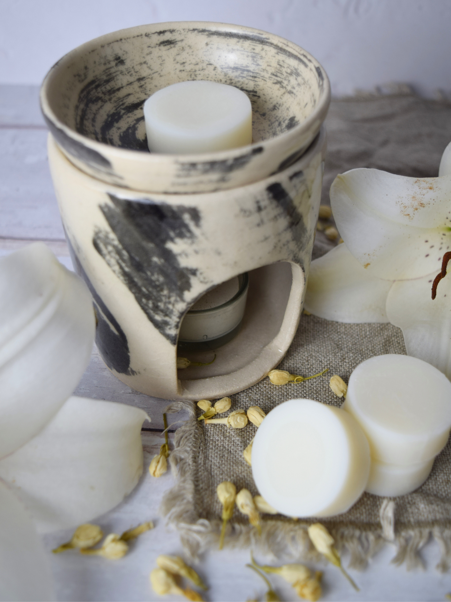 Duftlampe und Duftwachs mit weissen Blumen.