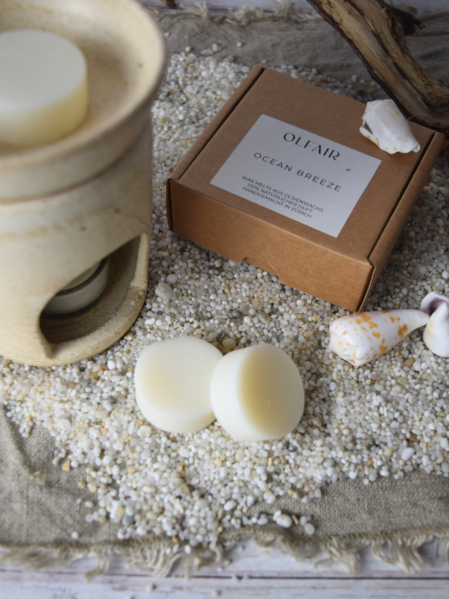 Duftwachs Ocean Breeze mit einer Duftlampe. Sand, Muscheln und Holz als Dkoreation.