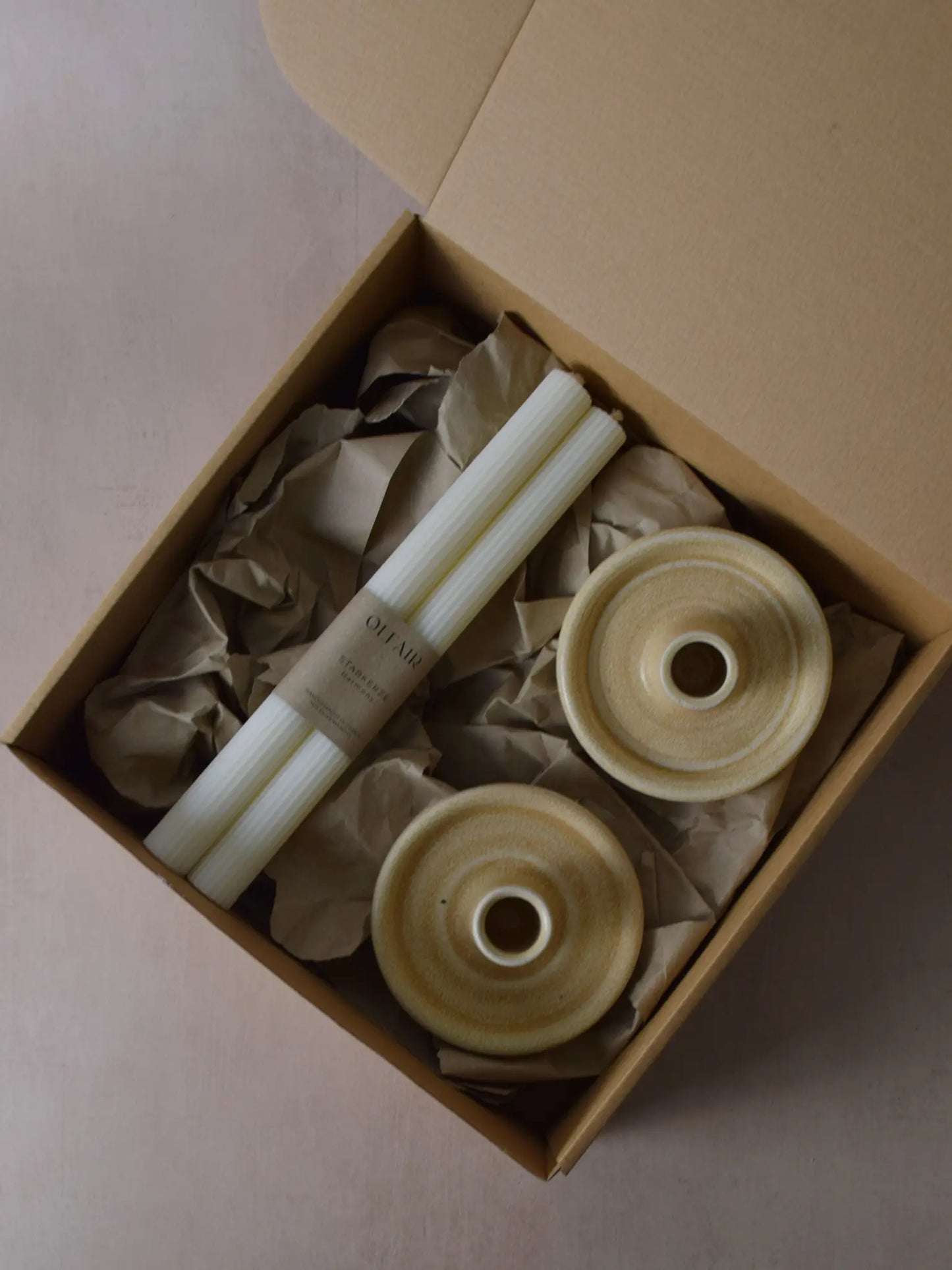 Geschenkset bestehend aus einem 2er-Set Stabkerzen mit kleinen Rillen und zwei Kerzenhaltern aus Keramik in beige.