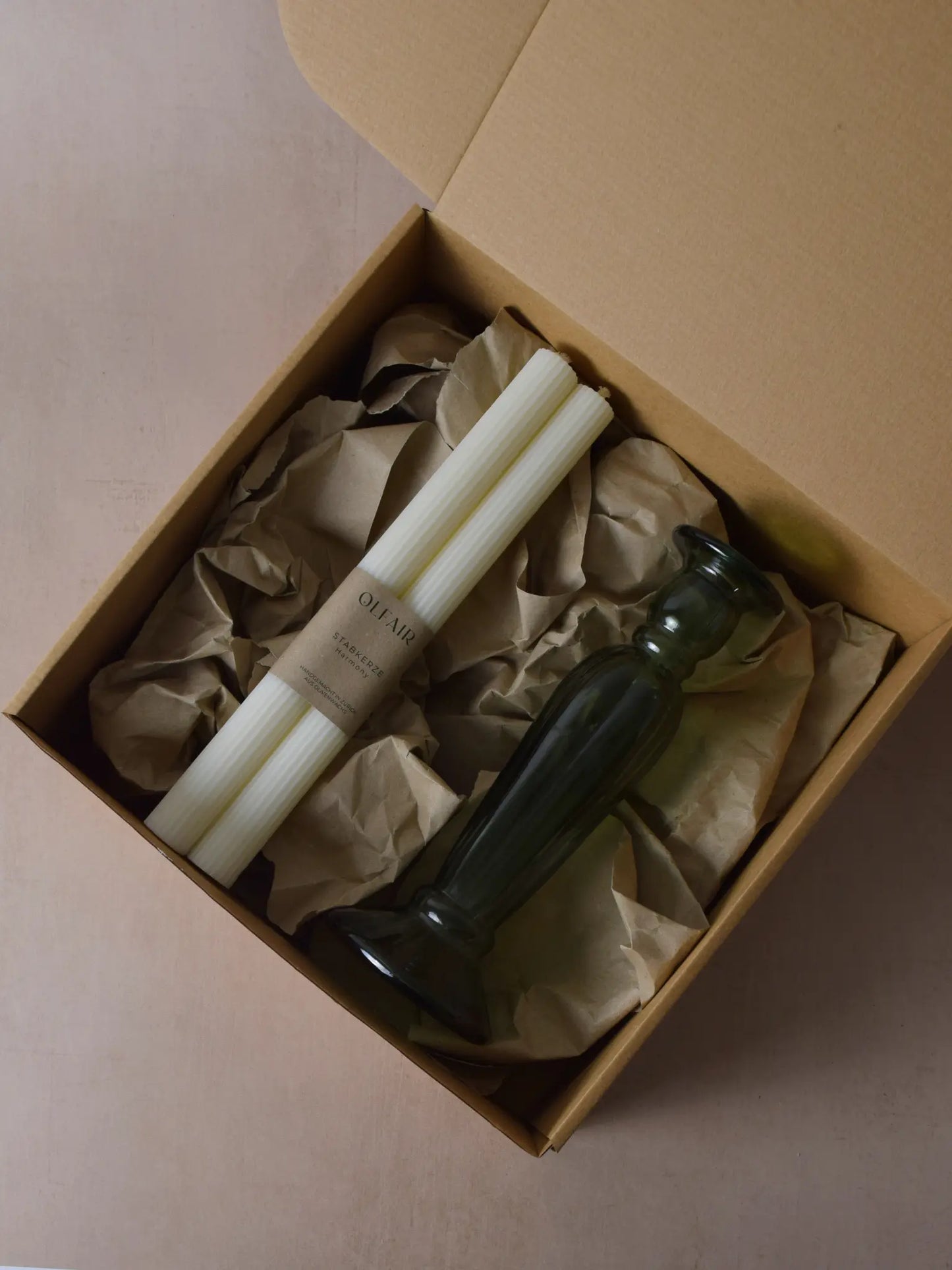 Geschenkset bestehend aus einem 2er-Set Stabkerzen mit kleinen Rillen und einem grünen Kerzenhalter aus Recycling-Glas
