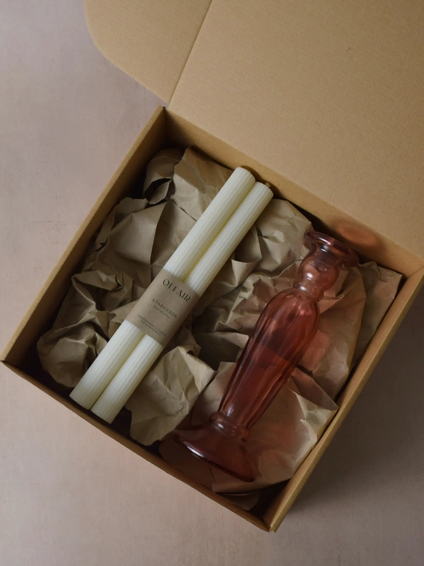 Geschenkset bestehend aus einem 2er-Set Stabkerzen mit kleinen Rillen und einem rosa Kerzenhalter aus Recycling-Glas