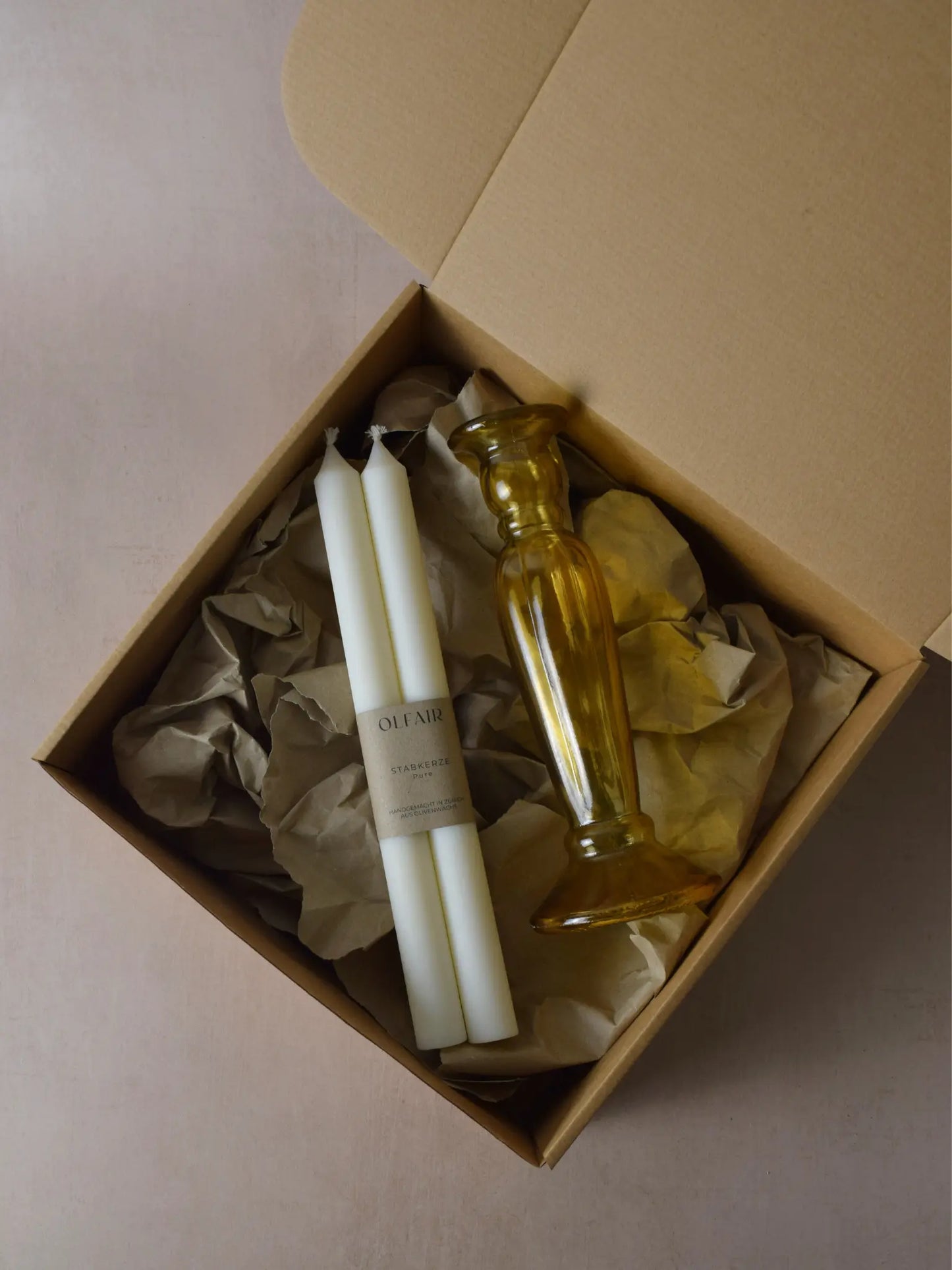 Geschenkset bestehend aus einem 2er-Set glatten Stabkerzen und einem bernsteinfarbenen Kerzenhalter aus Recycling-Glas