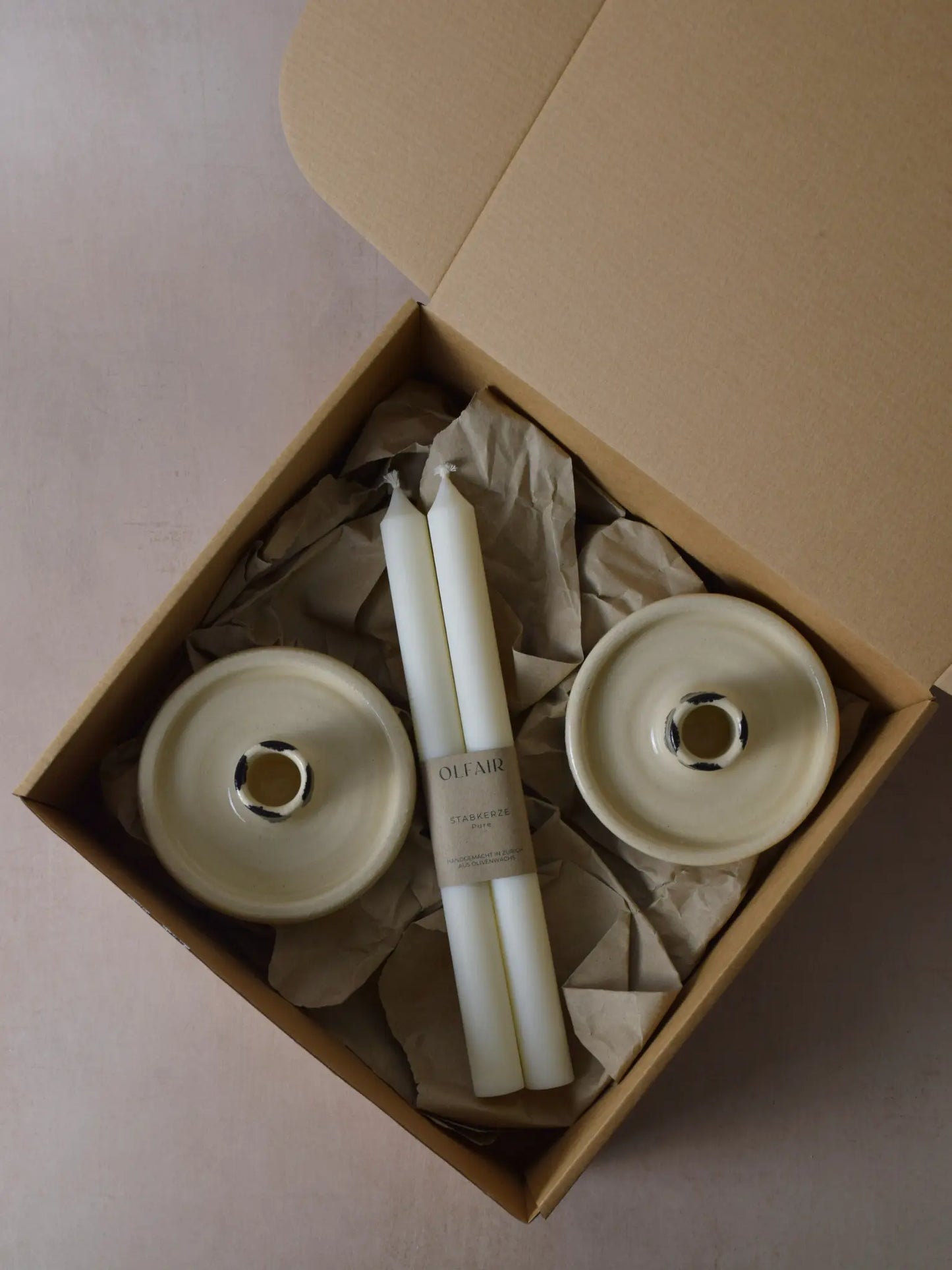 Geschenkset bestehend aus einem 2er-Set glatten Stabkerzen und zwei Kerzenhaltern aus Keramik schwarz/weiss gestreift.