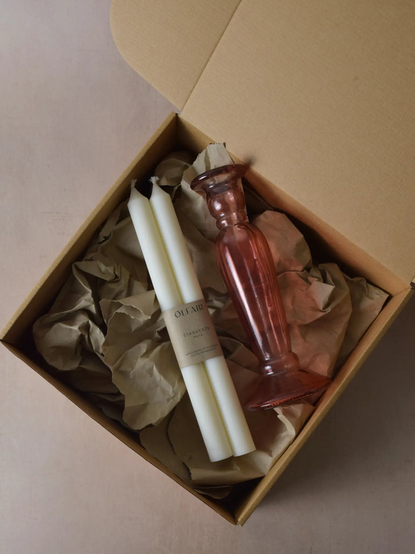 Geschenkset bestehend aus einem 2er-Set glatten Stabkerzen und einem rosa Kerzenhalter aus Recycling-Glas