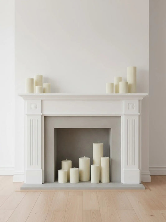 Unterschiedliche grosse Zylinderkerzen mit feinen Rillen in und auf einem weissen Kamin.
