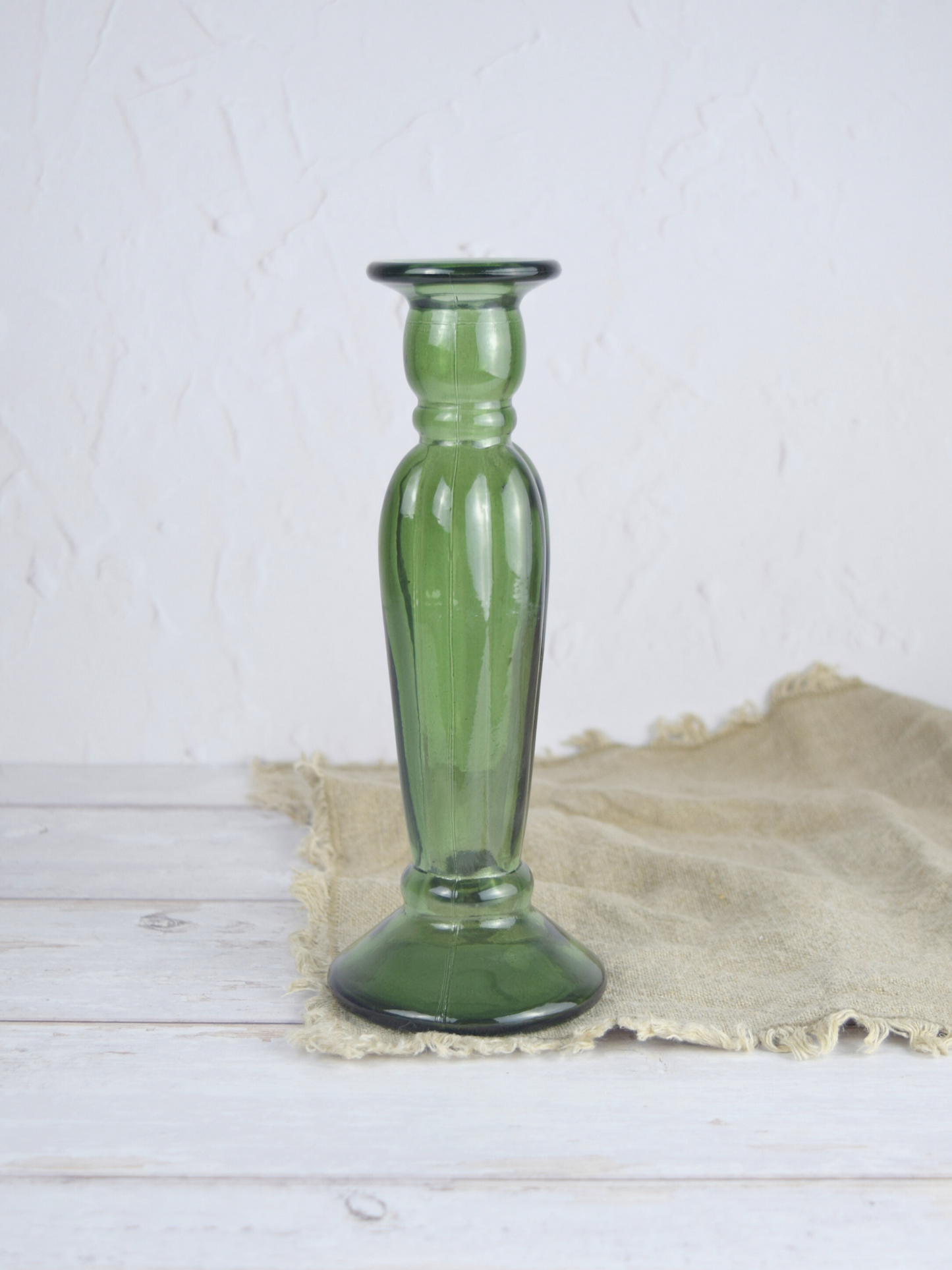 Grüner Kerzenhalter aus Recyclingglas auf einem braunen Tuch vor einem hellem Hintergrund