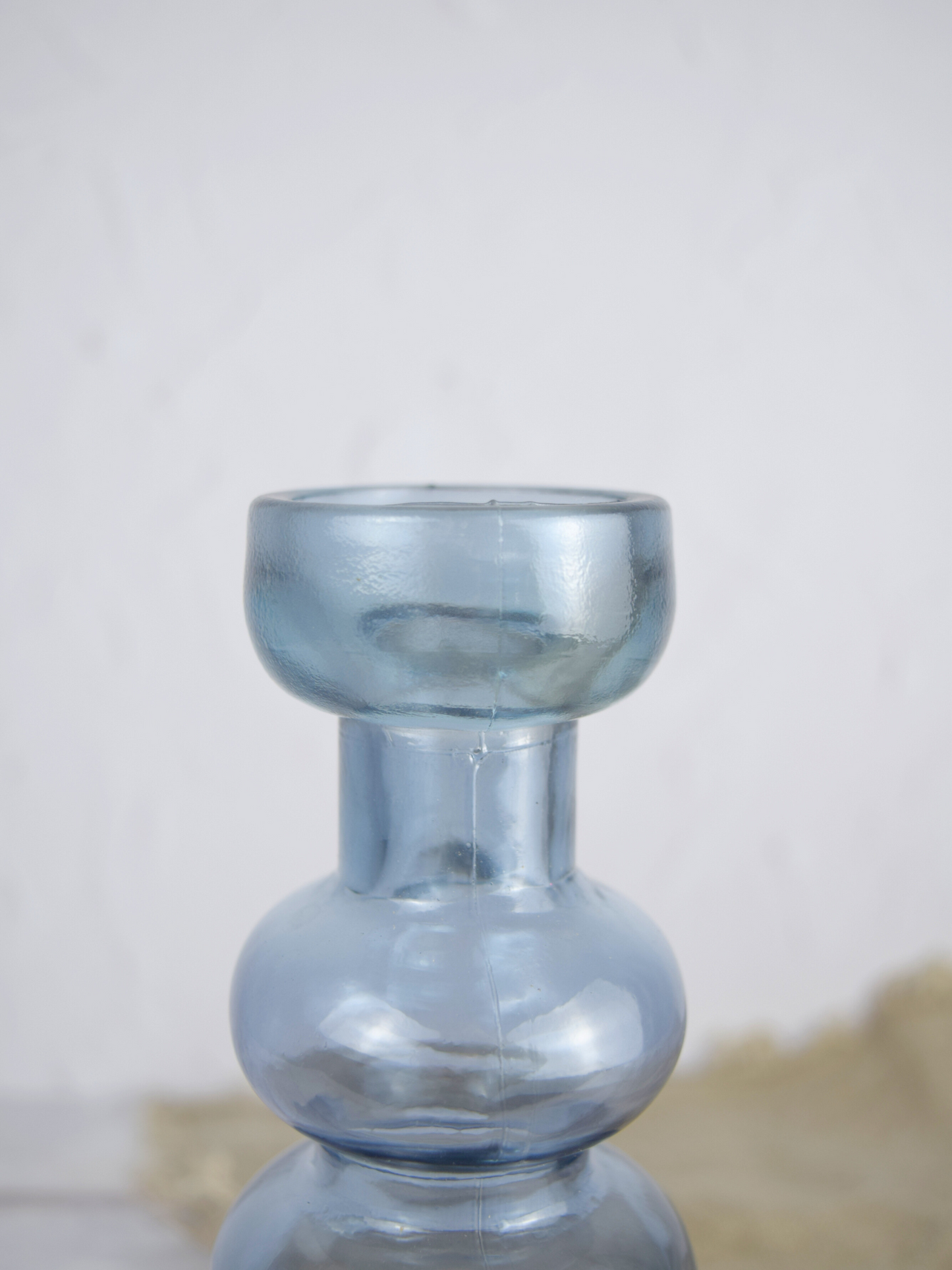 Nahaufnahme eines blauen, gewölbten Kerzenhalter vor einem weissen Hintergrund