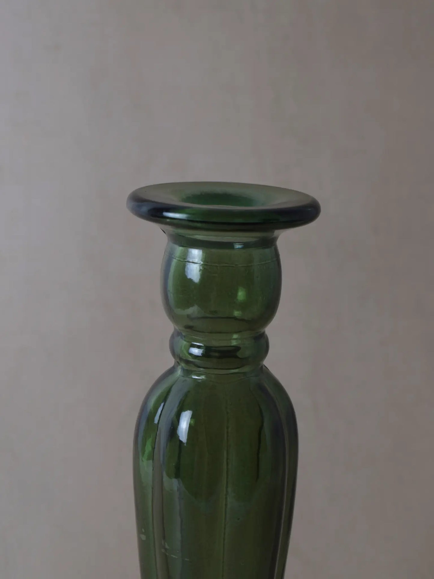 Nahaufnahme eines grünen Kerzenhalters aus Recyclingglas auf einem beigen Hintergrund.