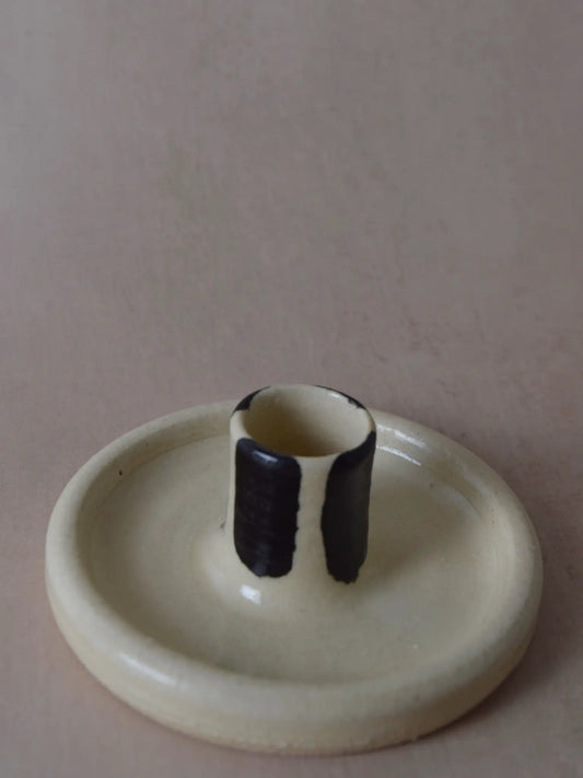 Nahaufnahme eines schwarz/weiss gestreiften Kerzenhalter aus Keramik vor einem beigen Hintergrund.