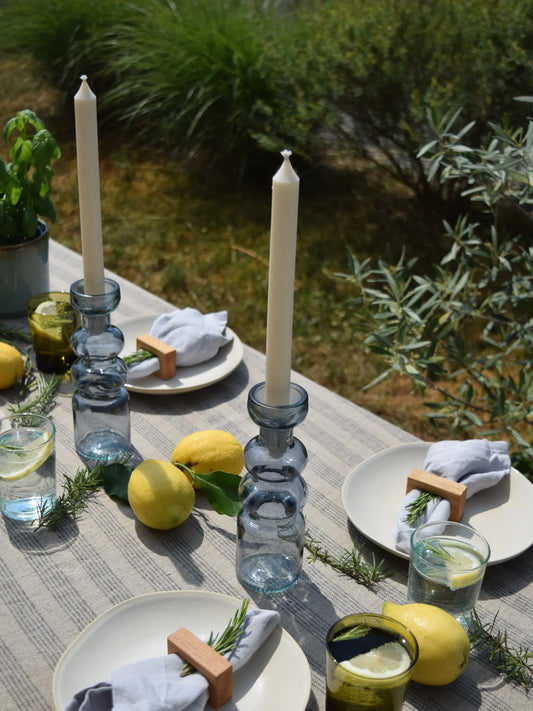 Blaufarbige Kerzenhalter mit Stabkerze auf einem sommerlich gedeckten Tisch