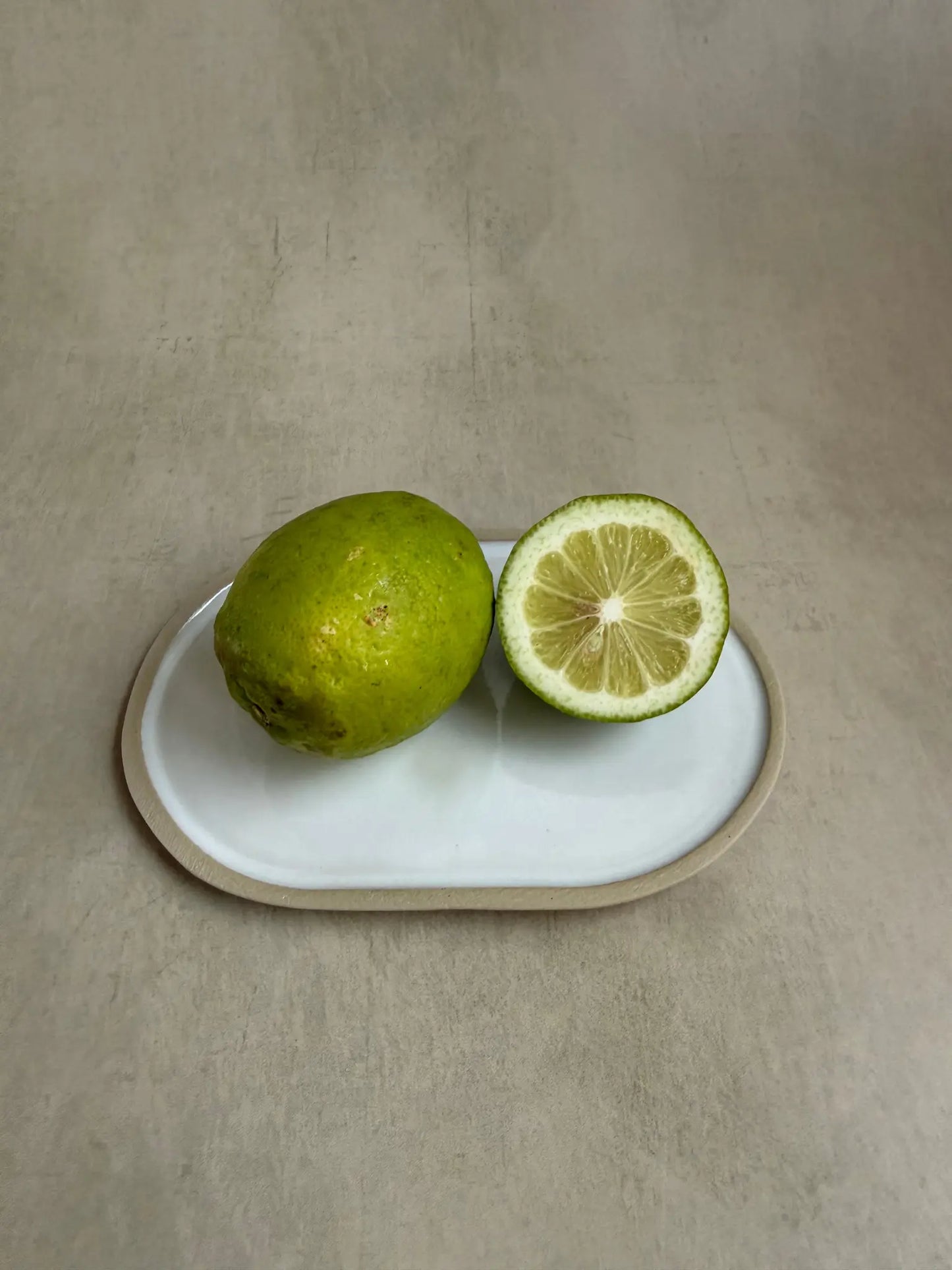 Ovaler Keramik Kerzenteller mit einer weissen Glasur mit Limetten.