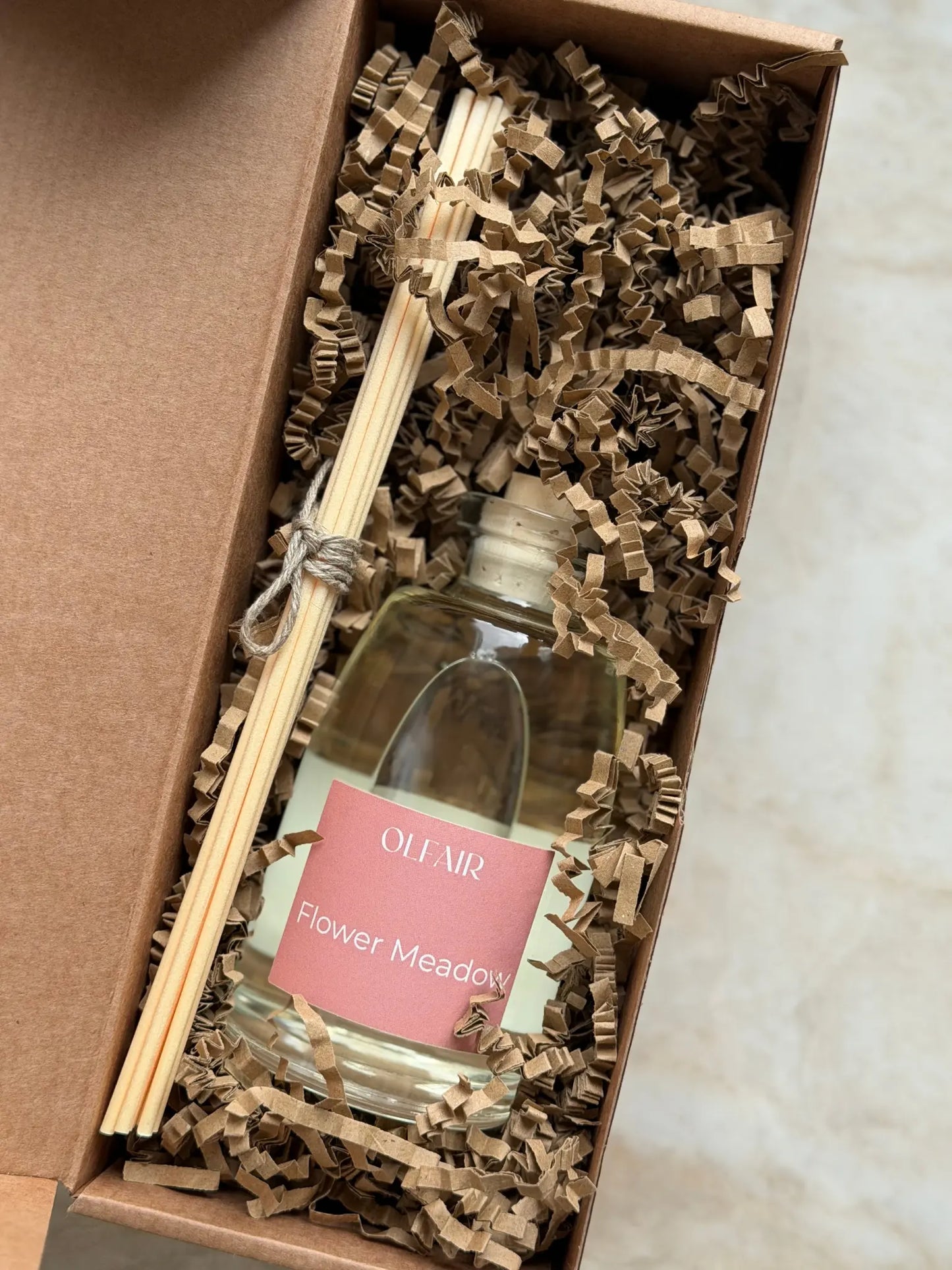 Raumduft mit dunkel rosa Etikette mit Stäbchen in einer Box.