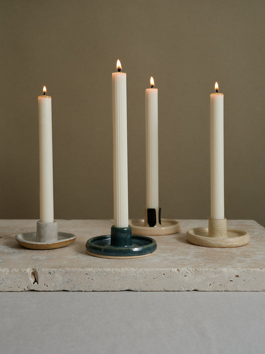 Filigrane Stabkerzen mit feinen Längsrillen auf einer Natursteinplatte, in naturweiss