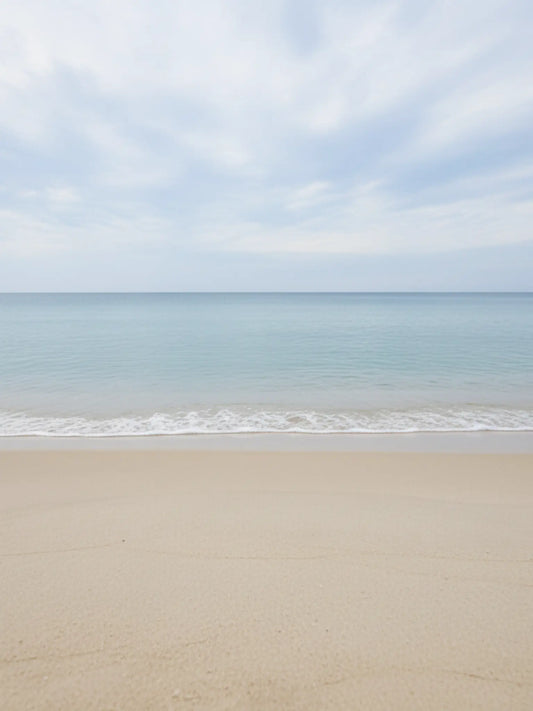 Ein Bild eines klaren, aufgeräumten Strandes mit leichten Wellen und etwas Wolken.
