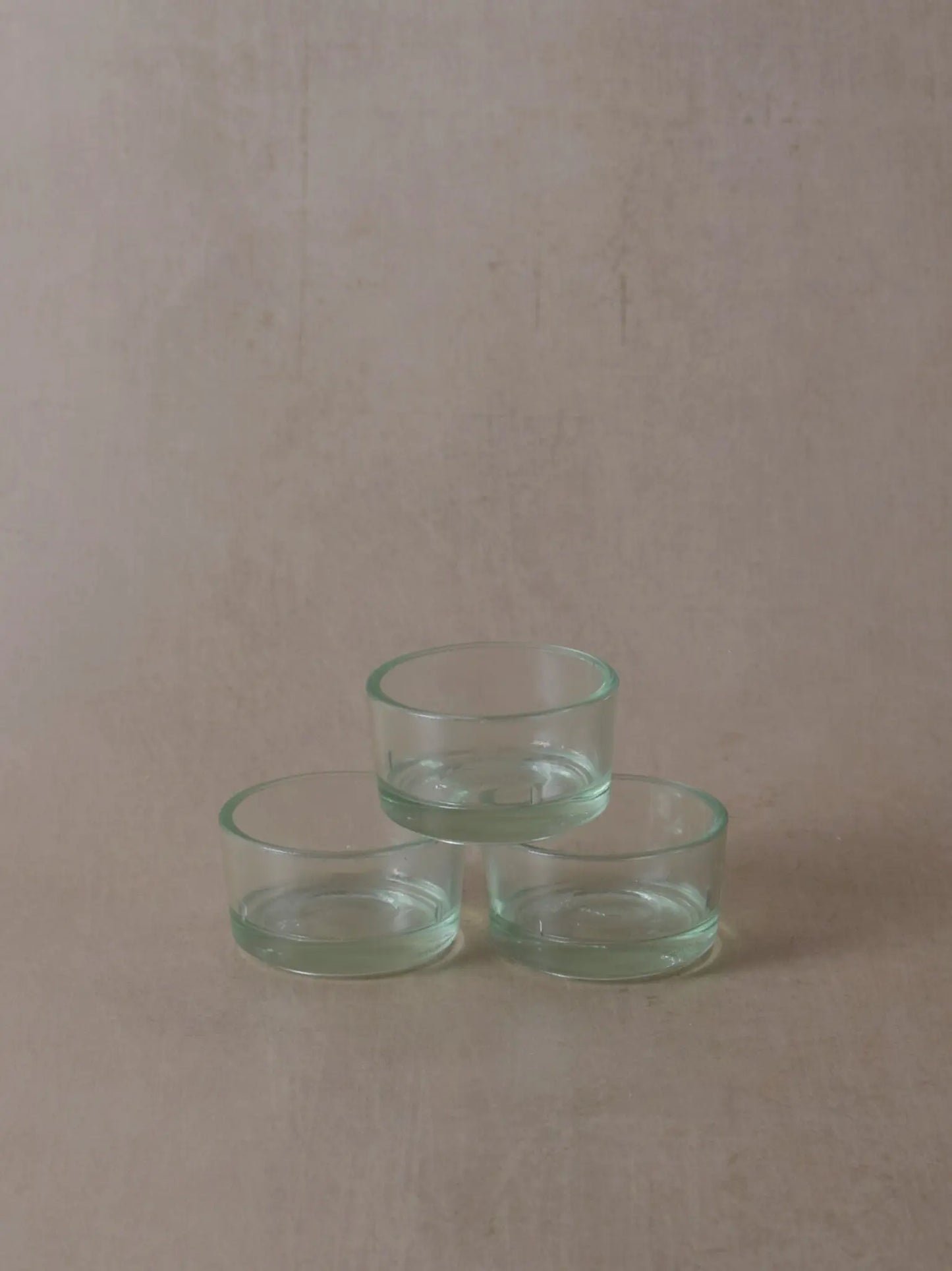 Pyramide mit Teelichthüllen aus Recyclingglas vor einem beigen Hintergrund.