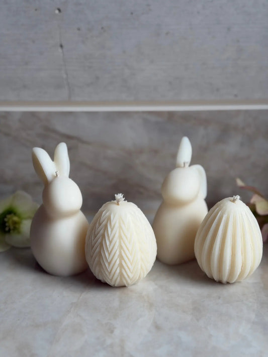 Zwei Osterhasen und zwei Ostereier Kerzen vor einem Marmor Hintergrund