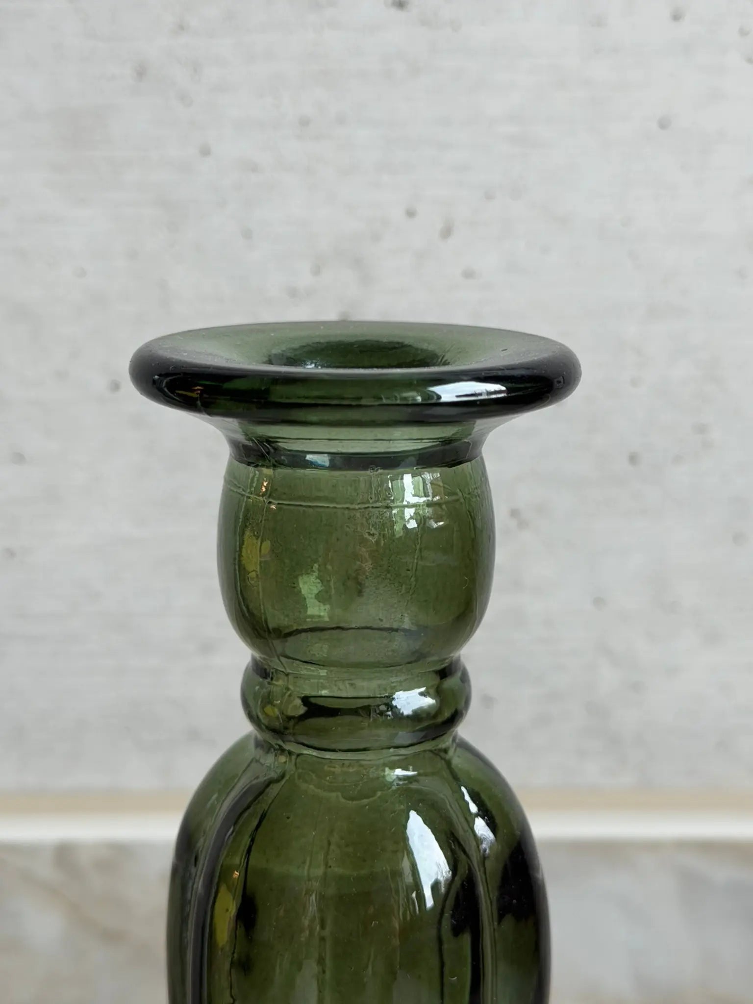 Nahaufnahme eines grünen Kerzenhalters aus Recyclingglas auf einem Marmor Hintergrund.