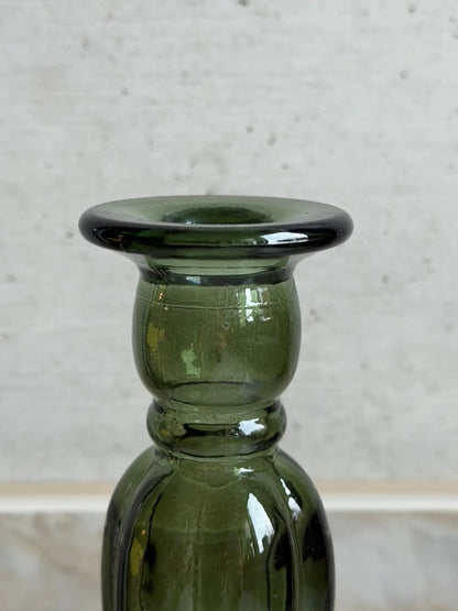 Nahaufnahme eines grünen Kerzenhalters aus Recyclingglas auf einem Marmor Hintergrund.