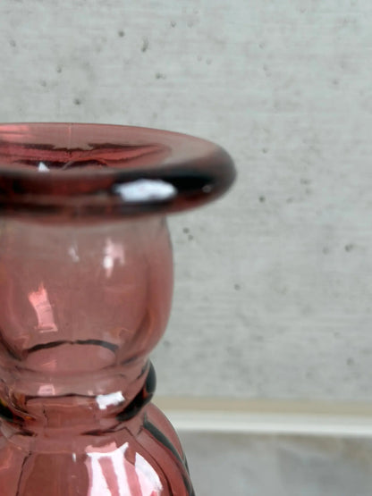 Teilaufnahme eines rosaarbigen Kerzenhalters aus Recyclingglas auf einem Marmor Hintergrund.