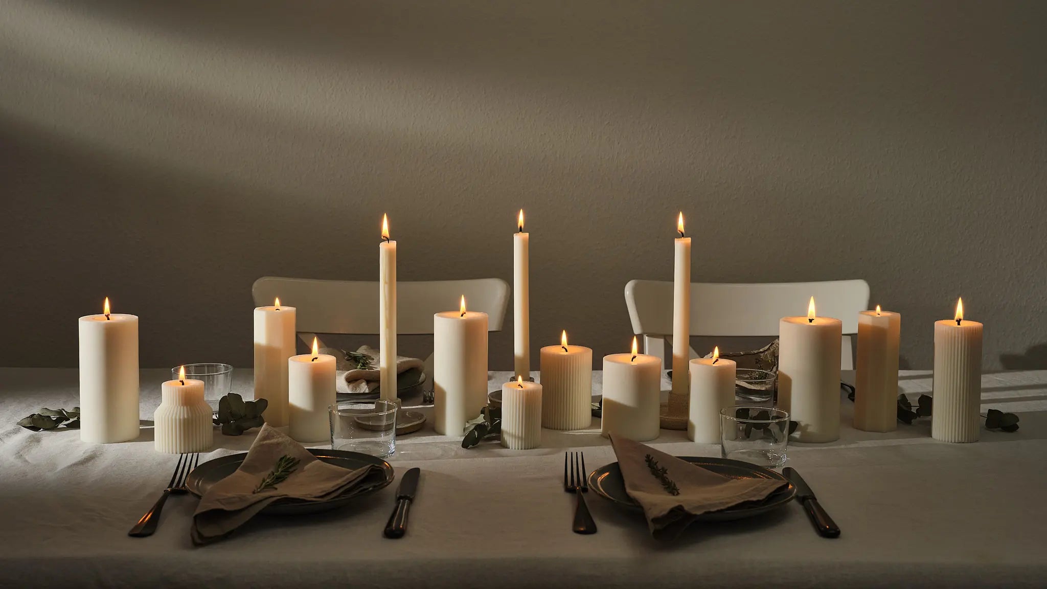 Stimmungsvolle Tischdekoration mit naturweissen Stab- und Zylinderkerzen, elegant arrangiert für ein gemütliches Abendessen