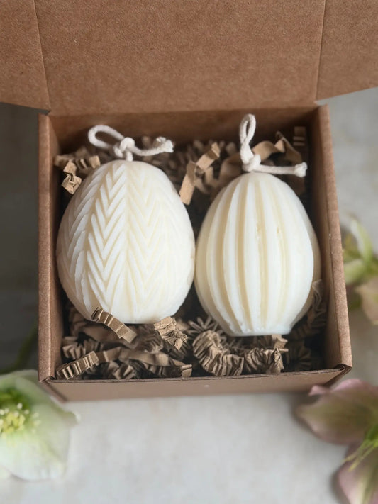 Zwei Ostereier Kerzen mit verschiedener Struktur in einer Geschenkbox auf einem Marmor Hintergrund.