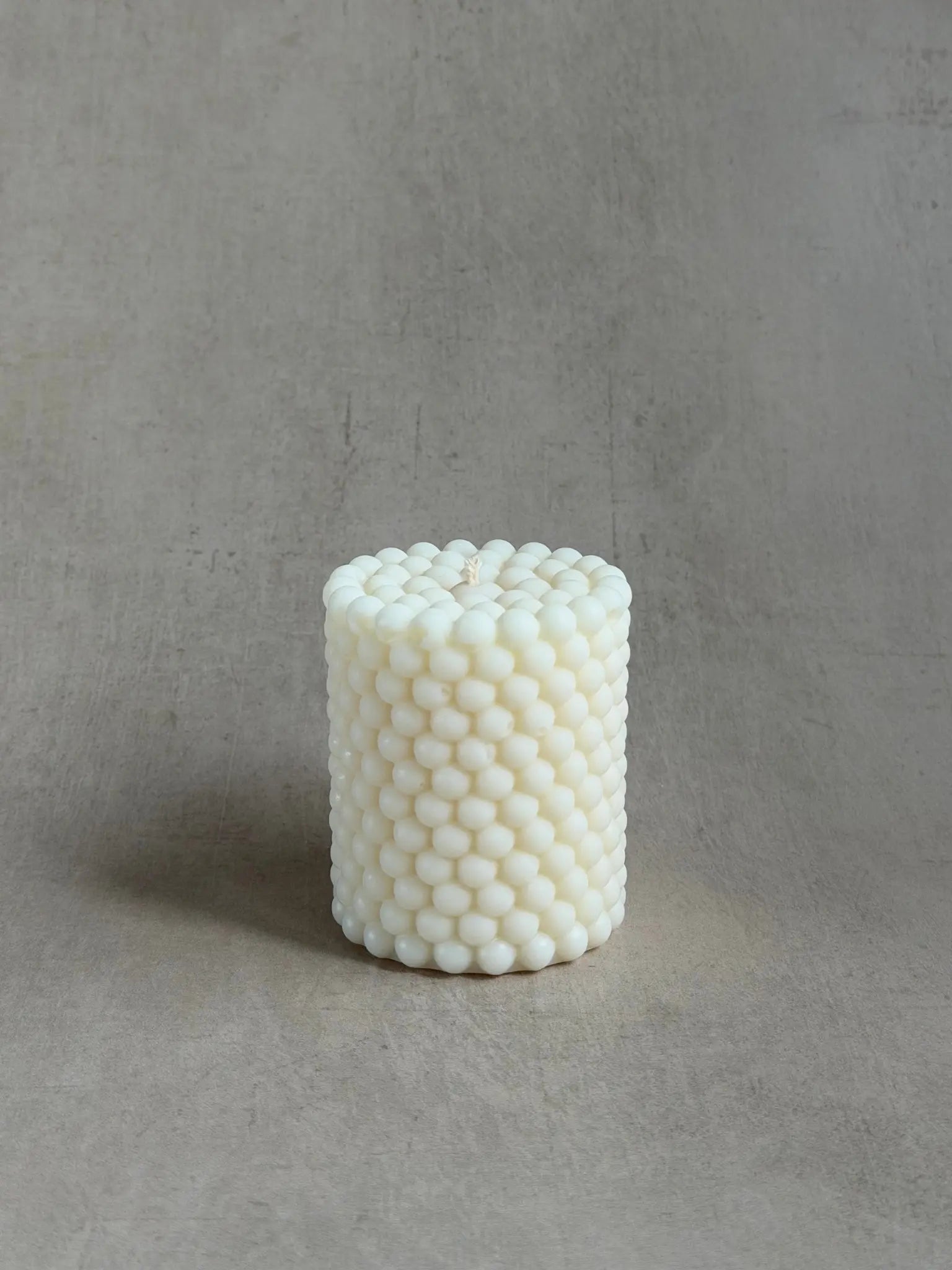 Zylinderkerze mit Bubbles vor einem beigen Hintergrund