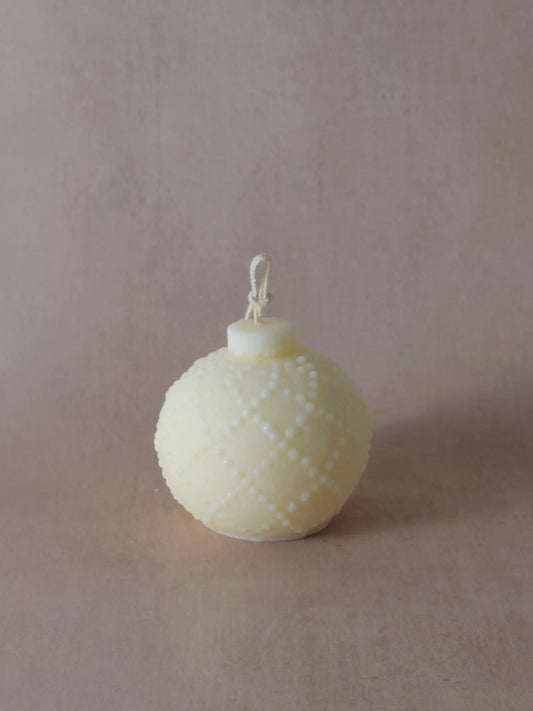 Naturfarbene Kerze in Weihnachtskugelform mit kleinen Tupfen.