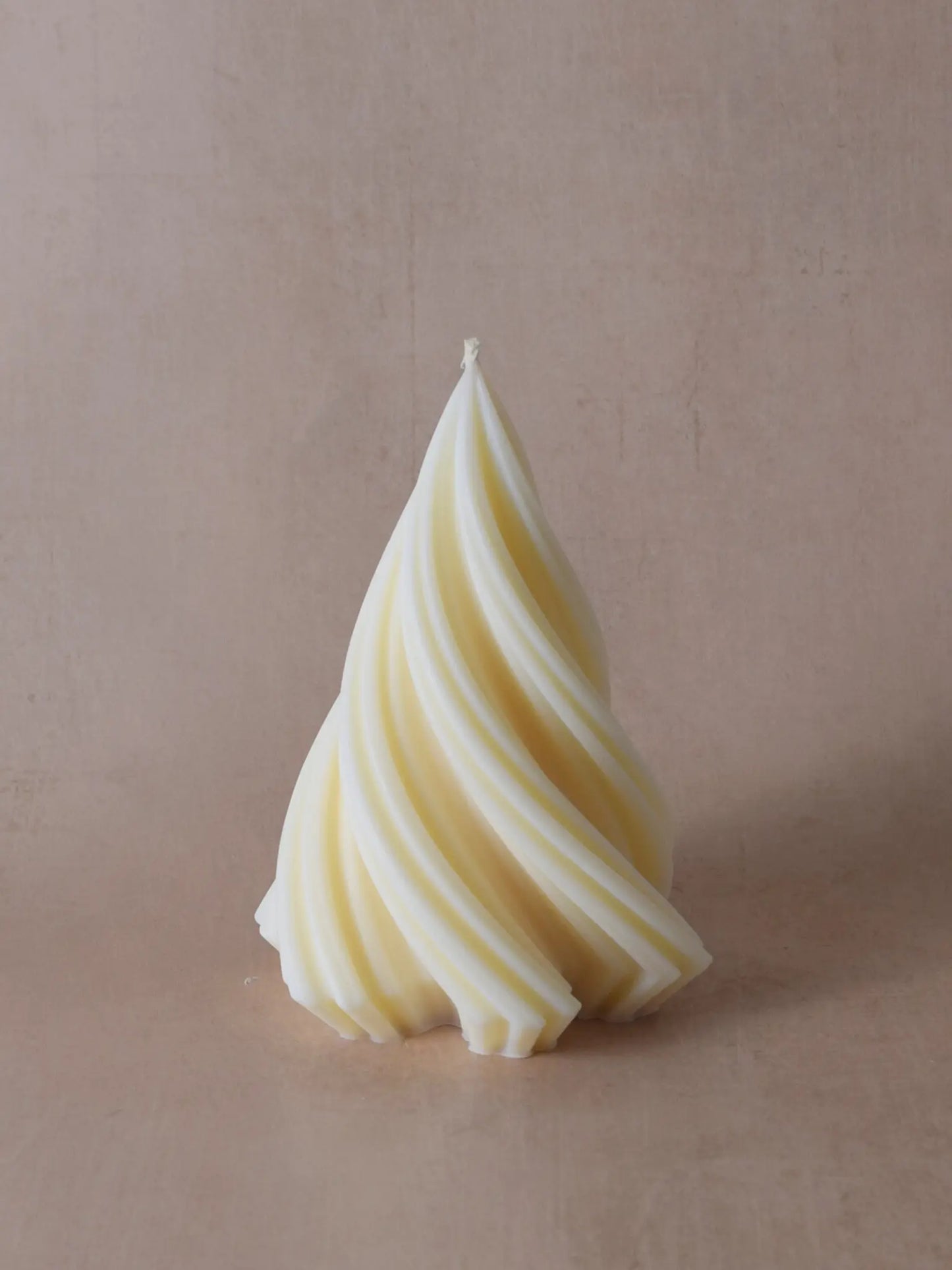 Grosse, naturfarbene Kerze in Weihnachtsbaumform vor einem beigen Hintergrund.