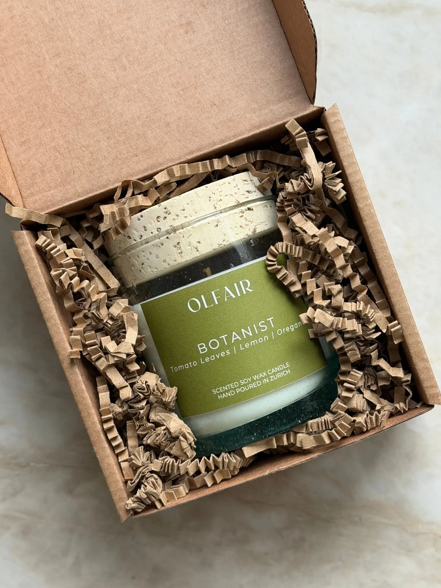 Geschenkbox mit Duftkerze Botanist vor einem Marmor Hintergrund.