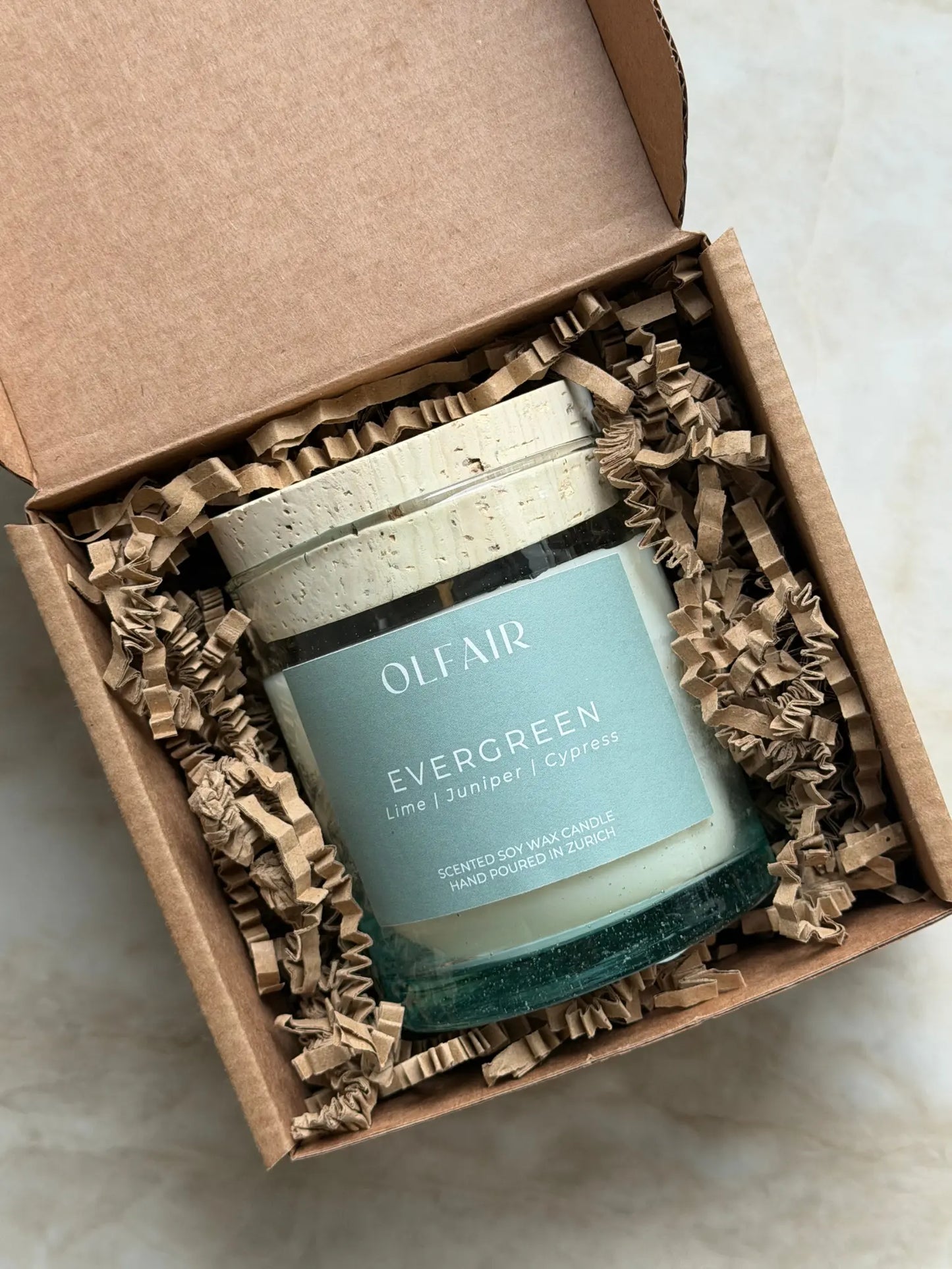 Geschenkbox mit Duftkerze Evergreen vor einem Marmor Hintergrund.