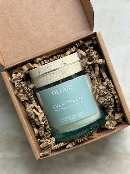 Geschenkbox mit Duftkerze Evergreen vor einem Marmor Hintergrund.