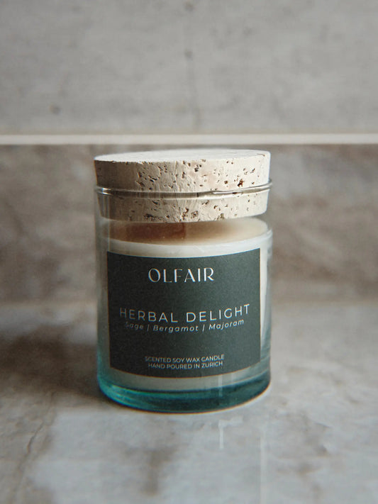 Duftkerze Herbal Delight vor einem Marmor Hintergrund.