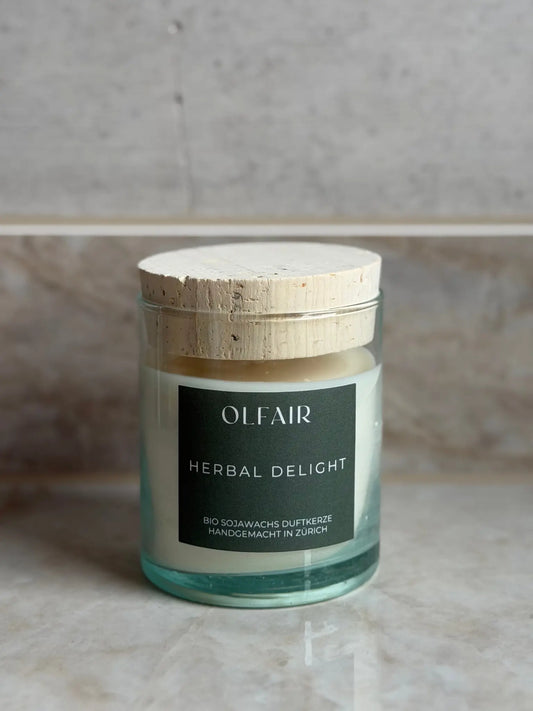 Duftkerze Herbal Delight vor einem Marmor Hintergrund.