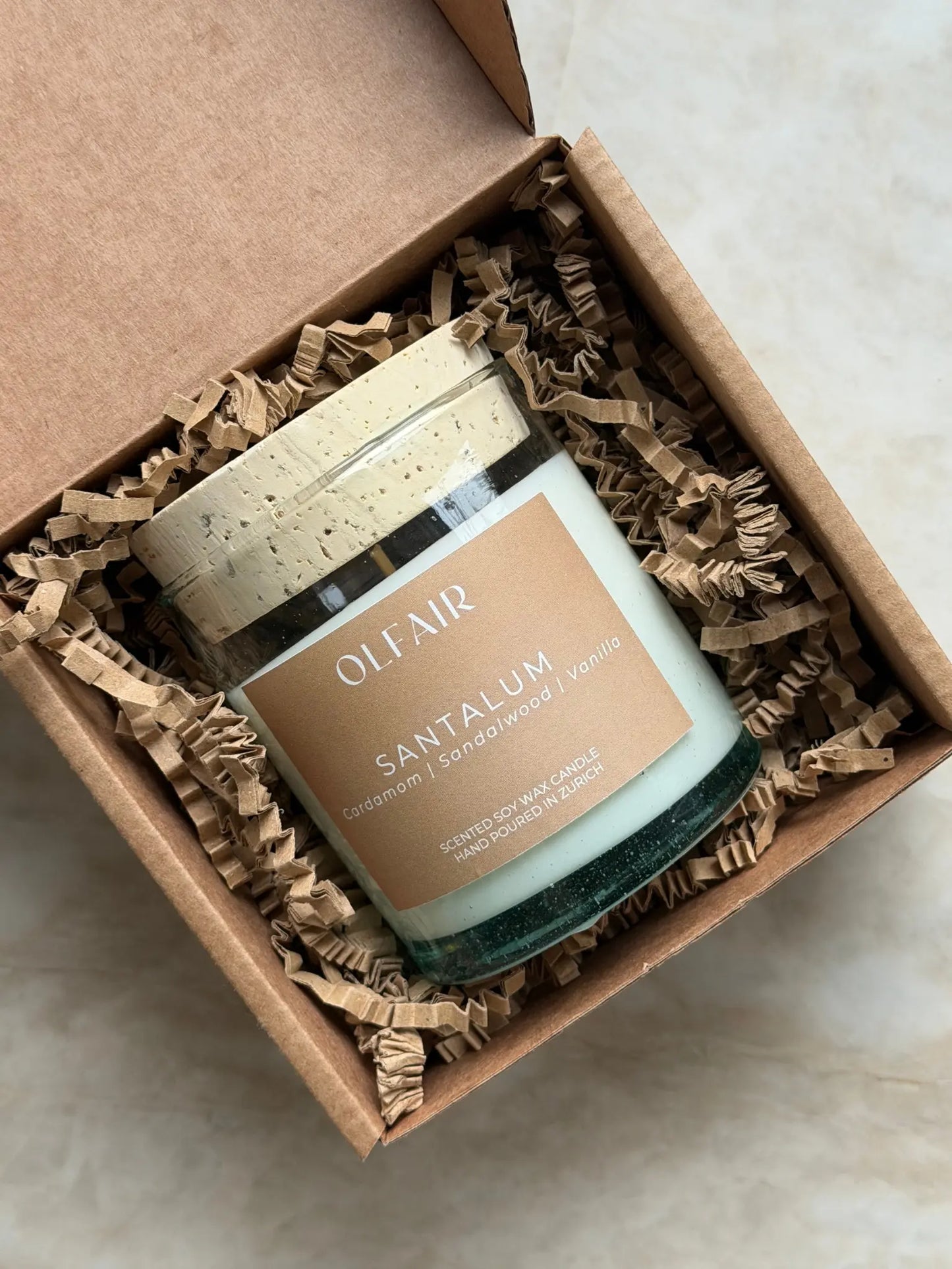 Geschenkbox mit Duftkerze Santalum vor einem Marmor Hintergrund.