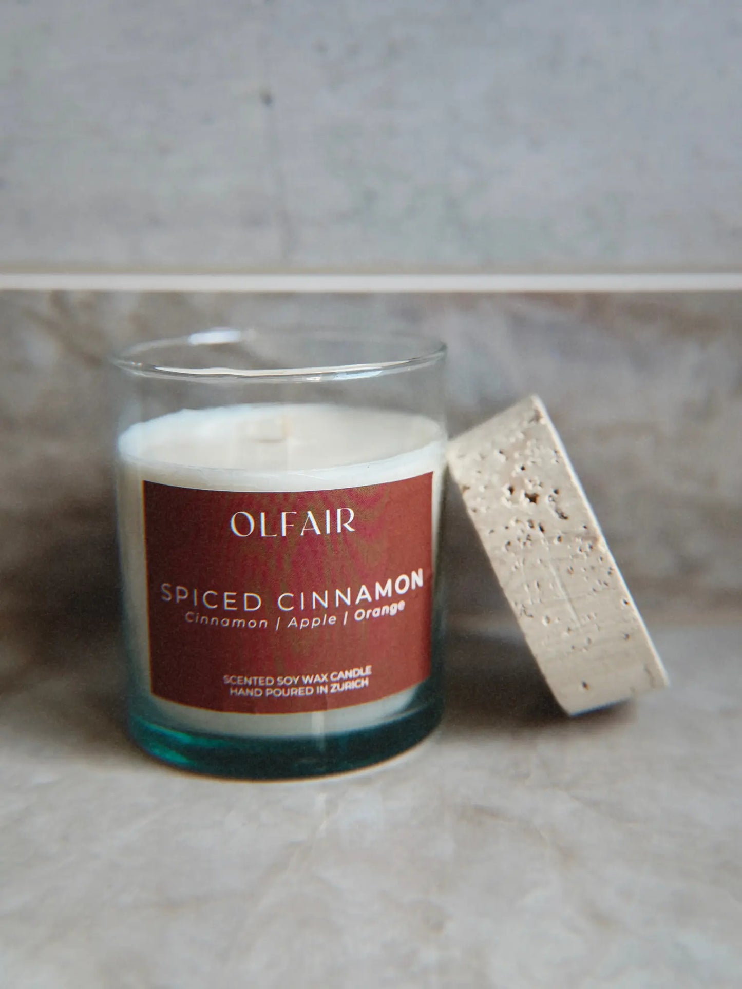 Duftkerze Spiced Cinnamon mit Deckel vor einem Marmor Hintergrund.
