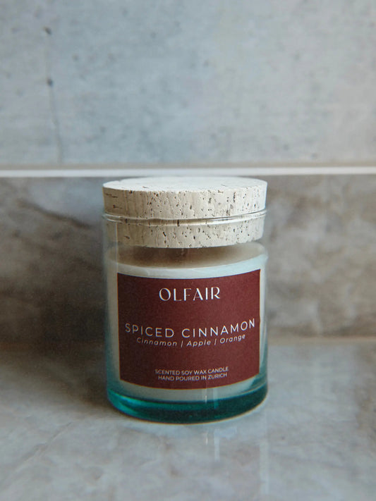 Duftkerze Spiced Cinnamon vor einem Marmor Hintergrund.