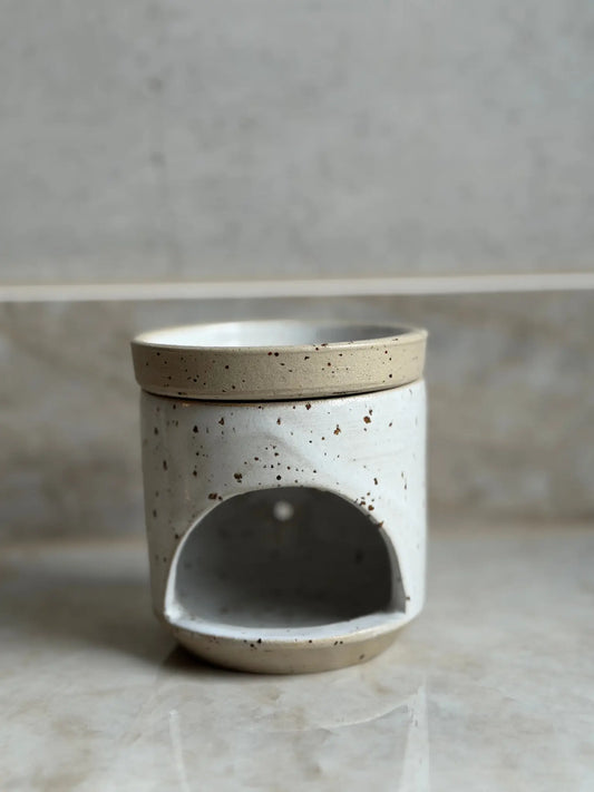 Duftlampe mit einer hellen Glasur vor einem Marmor Hintergrund