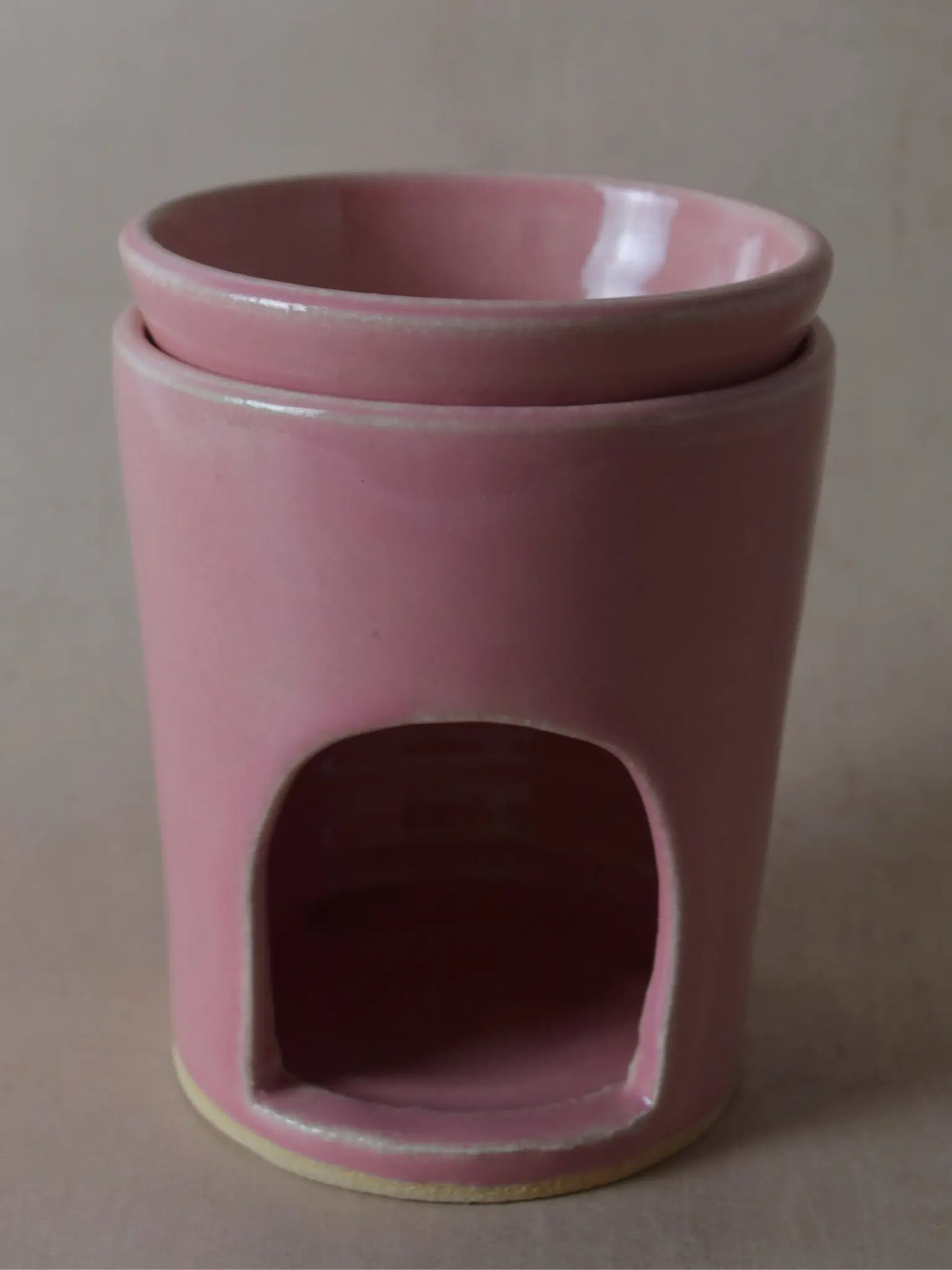 Nahaufnahme einer Duftlampe in rosa auf einem beigen Hintergrund.