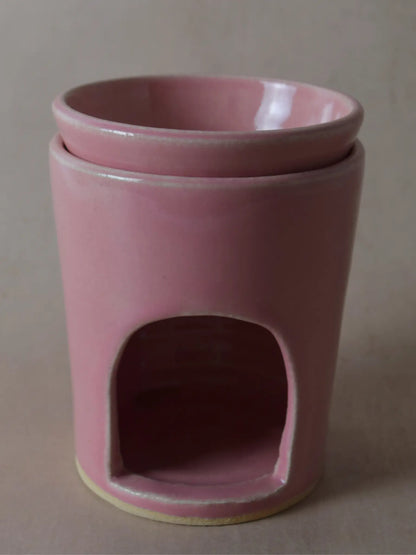 Nahaufnahme einer Duftlampe in rosa auf einem beigen Hintergrund.
