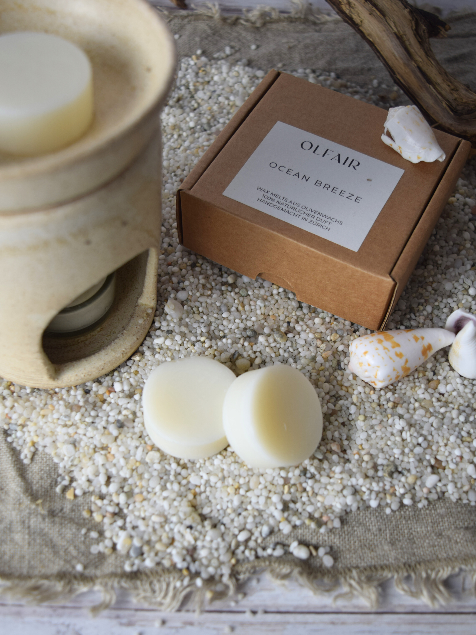 Duftwachs Ocean Breeze mit einer Duftlampe. Sand, Muscheln und Holz als Dkoreation.