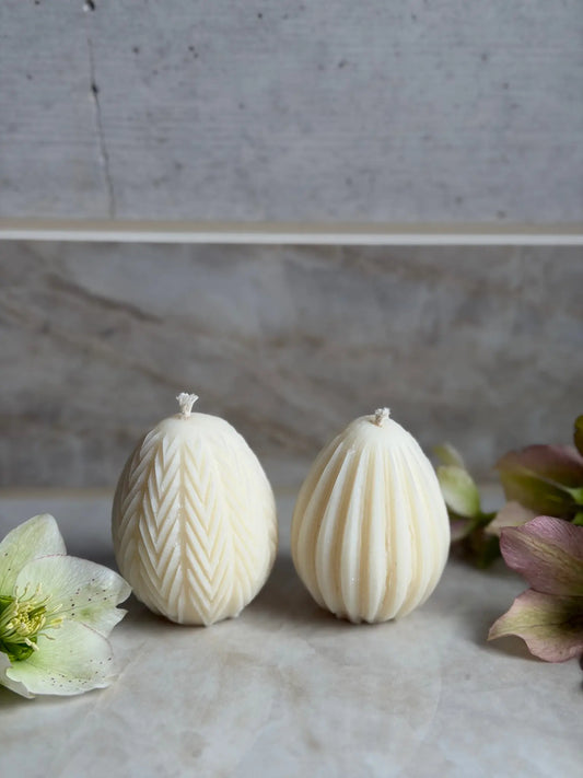 Zwei Ostereier Kerzen mit verschiedener Struktur auf Marmor Hintergrund.