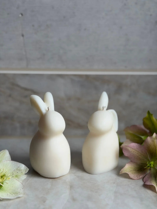 Zwei Osterhasen Kerzen vor einem Marmor Hintergrund.