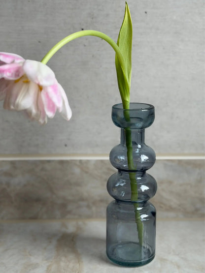 Blauer, gewölbter Kerzenhalter vor einem Marmor Hintergrund mit einer Blume