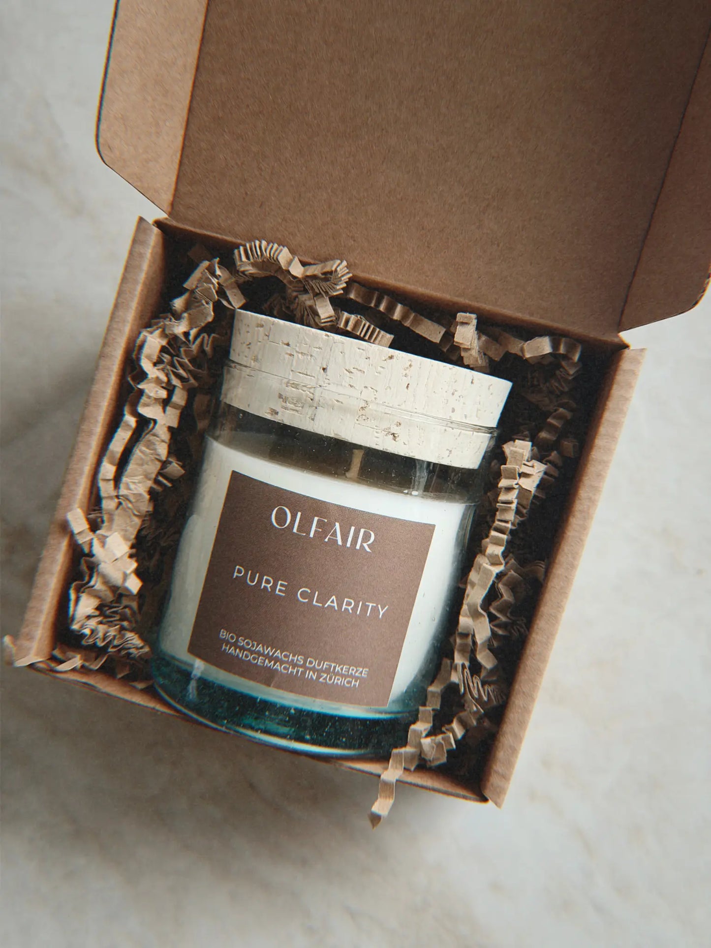 Geschenkbox mit Duftkerze Pure Clarity vor einem Marmor Hintergrund.