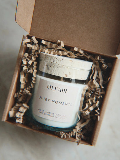 Geschenkbox mit Duftkerze Quiet Moments vor einem Marmor Hintergrund.
