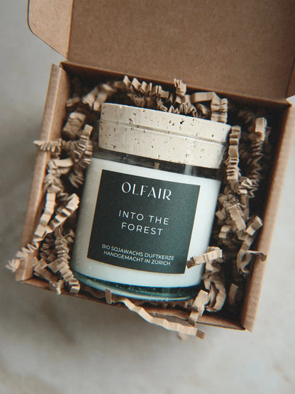 Geschenkbox mit Duftkerze Into the Forest vor einem Marmor Hintergrund.