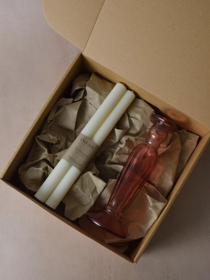 Geschenkset bestehend aus einem 2er-Set Stabkerzen mit kleinen Rillen und einem rosa Kerzenhalter aus Recycling-Glas
