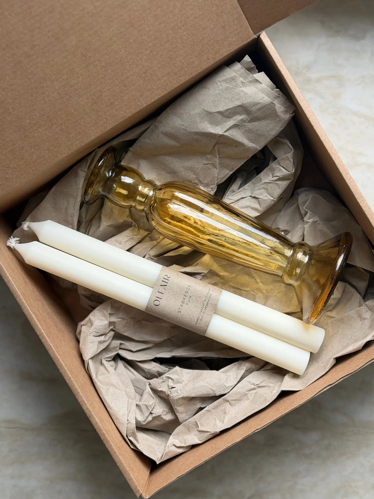 Geschenkset bestehend aus einem 2er-Set glatten Stabkerzen und einem bernsteinfarbenen Kerzenhalter aus Recycling-Glas