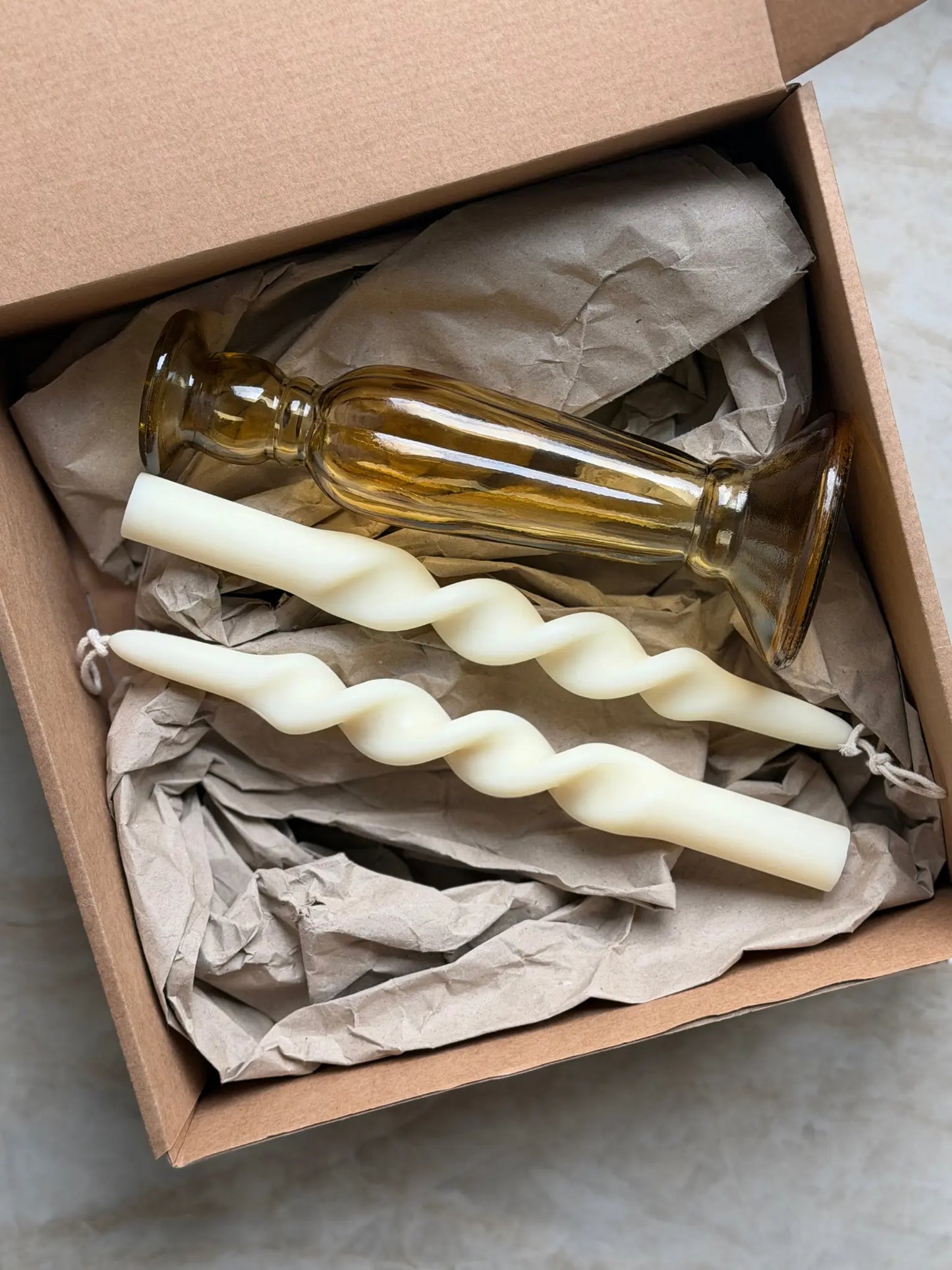 Geschenkset bestehend aus einem 2er-Set gedrehter Stabkerzen und einem bernsteinfarbenen Kerzenhalter aus Recycling-Glas